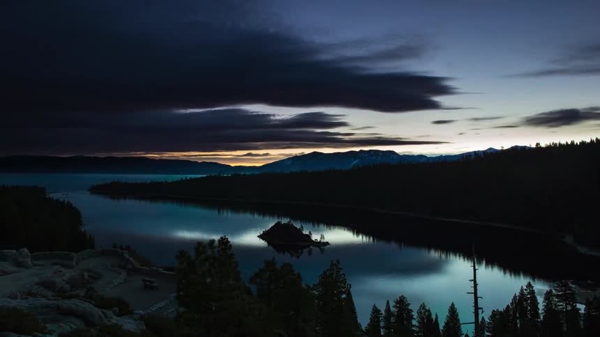 The sun sets over a lake near a mountain