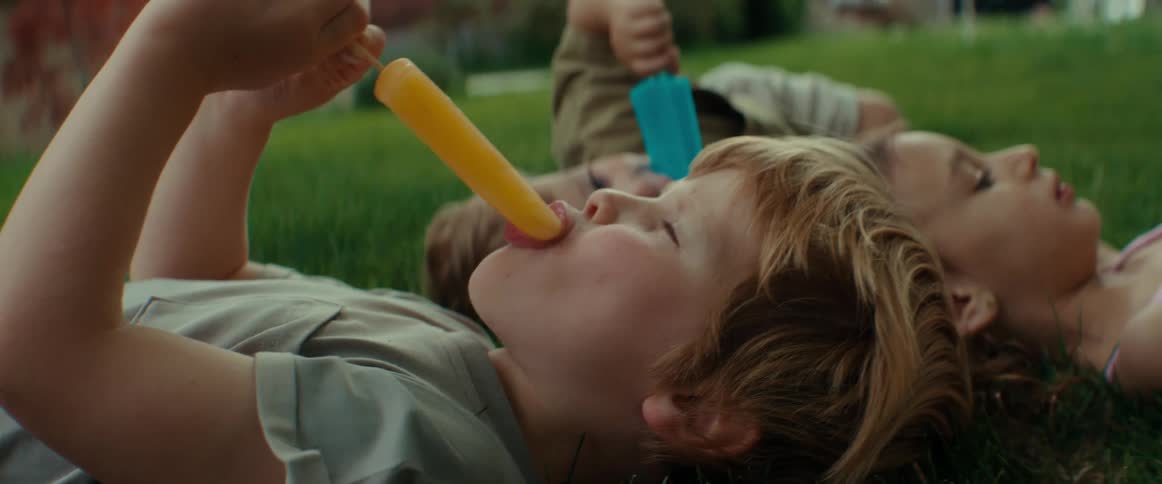 Children eat popsicles on the lawn