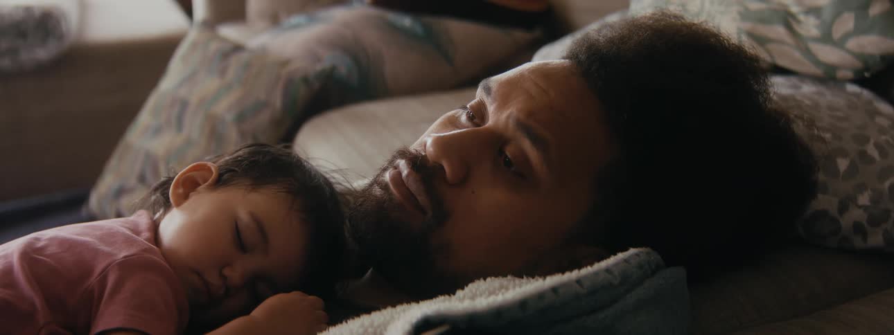 A father is worrying about something while laying down with his child