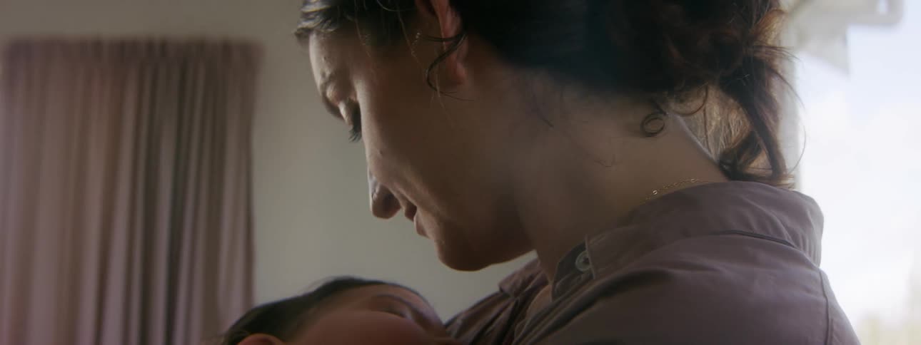 A woman is holding her newborn baby indoors