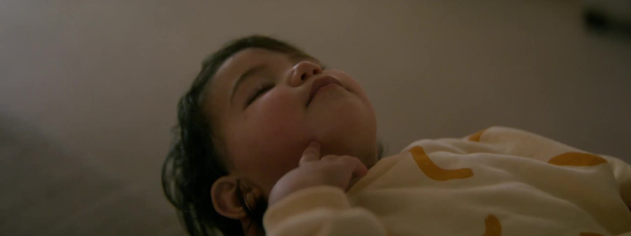 A baby smiling and touching their face