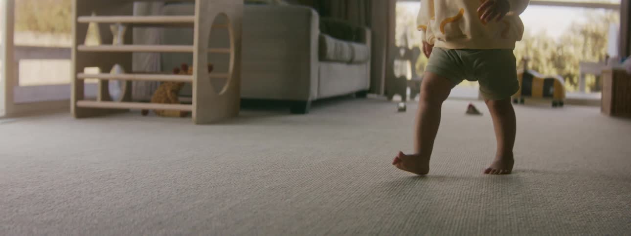 A toddler is walking in a living room of a house