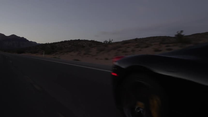 A black car driving down a road