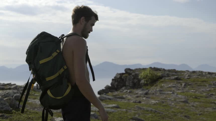 Active male hiker trekking on a rugged mountain ridge under a dramatic overcast sky.