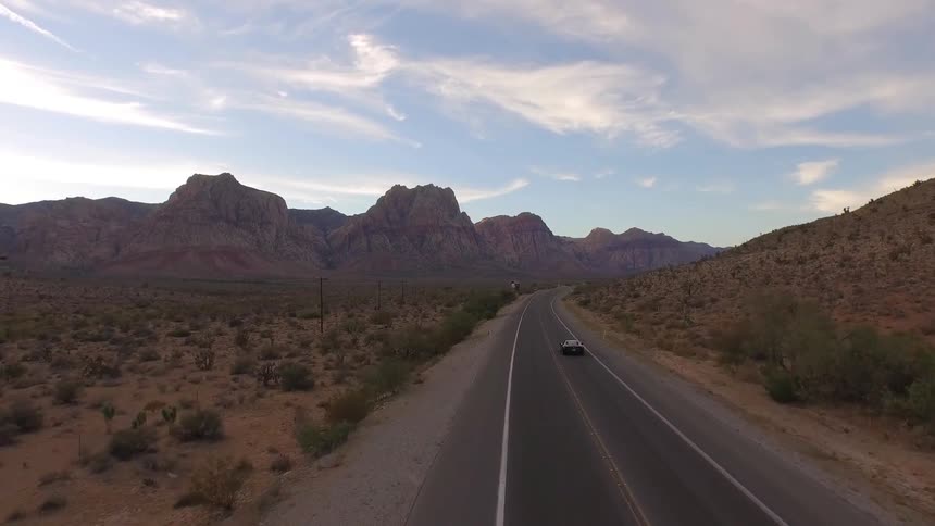 A car drives down a road near a mountain