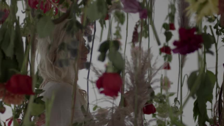 A woman walks past vines covered with flowers