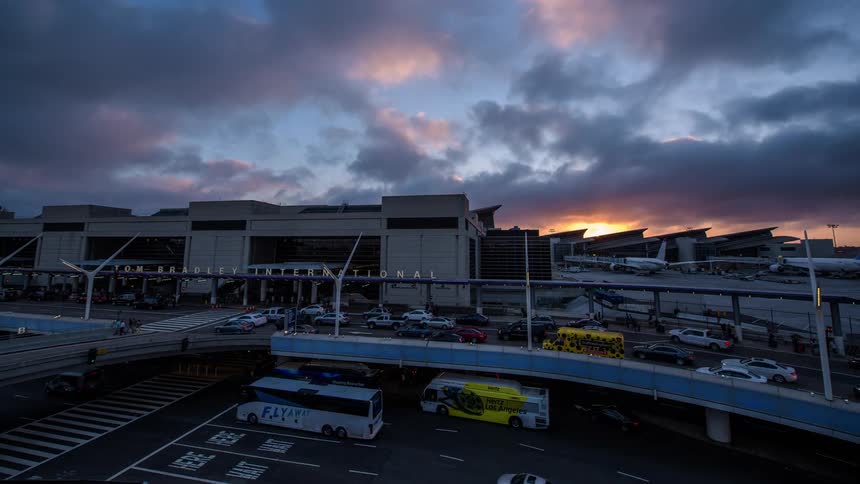 A hyperlapse shot of hectic traffic flowing past LAX airport as horizon brightens then darkens