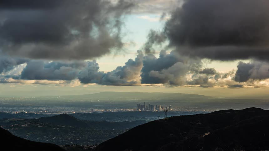 Storm clouds roll over the mountains and a city