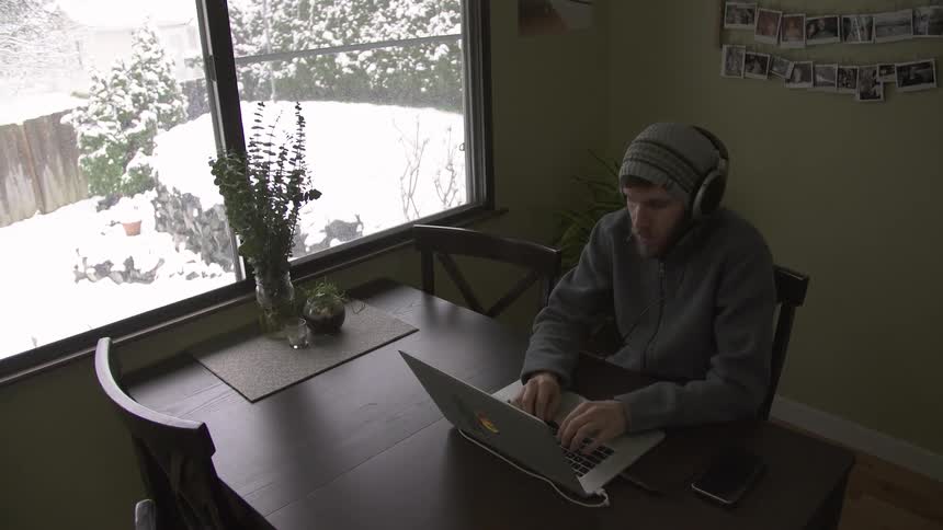 A man is using a laptop by a window