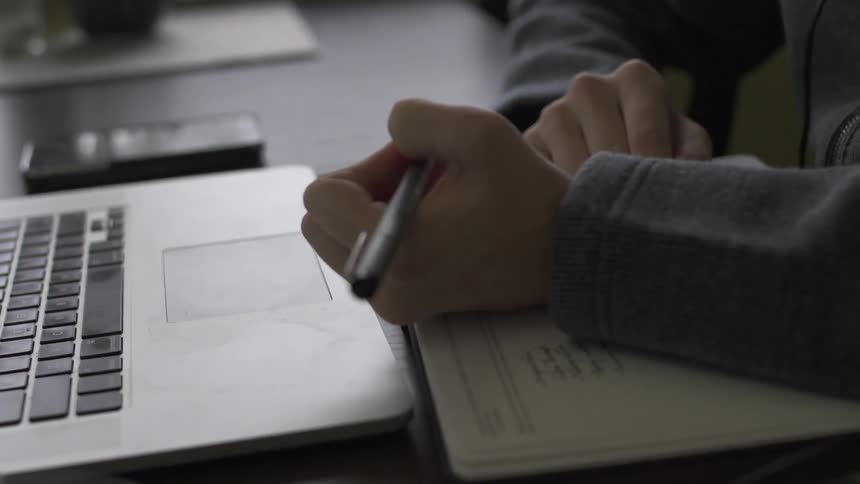 A man writes on a notebook