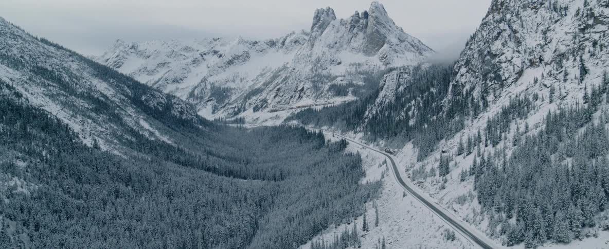 A road runs through snow covered mountains