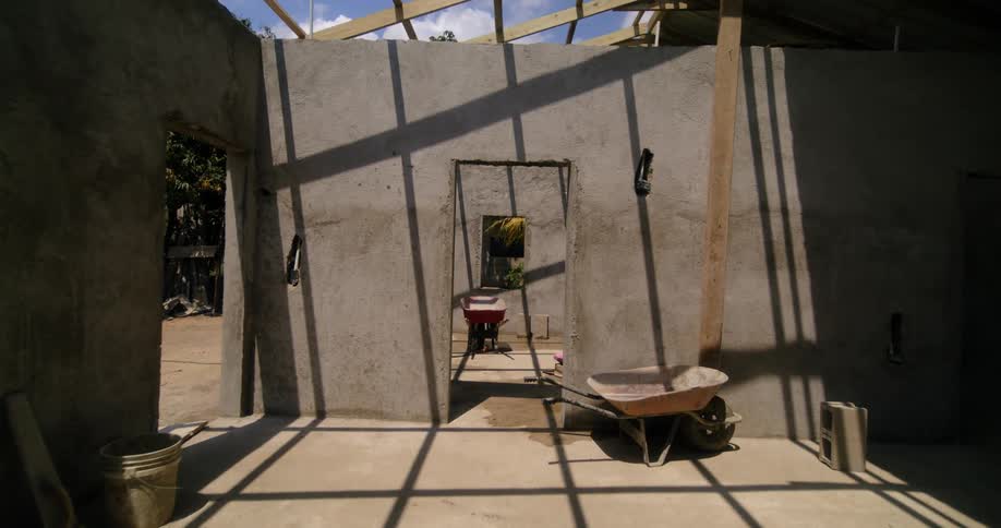 Wheelbarrows and ladders are in rooms of a building under construction