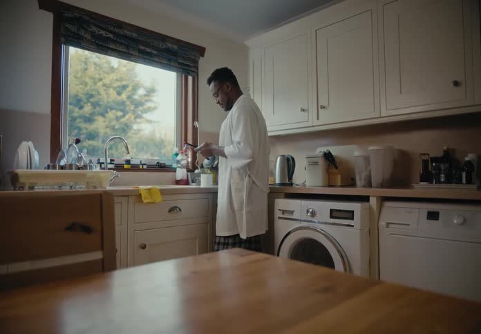 Man stands in kitchen near sink scrolling on smartphone