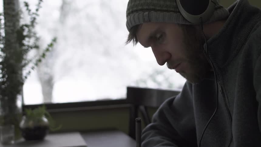 A man is writing as it snows outside