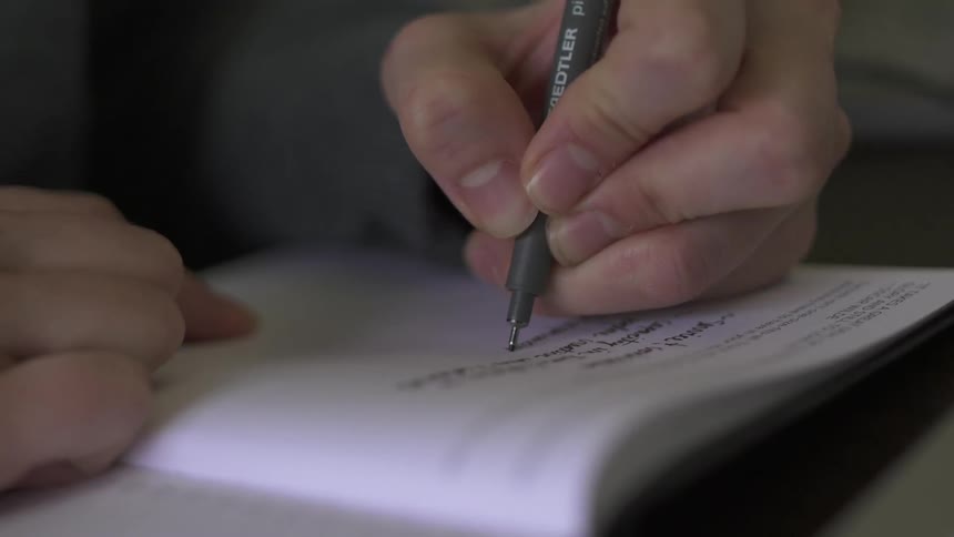 A person is writing in a notebook