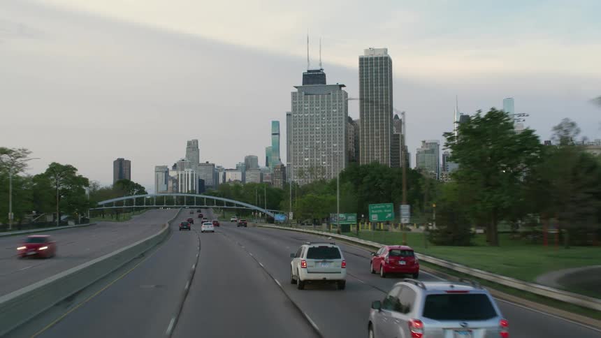 Vehicles drive down a multi lane highway headed toward downtown