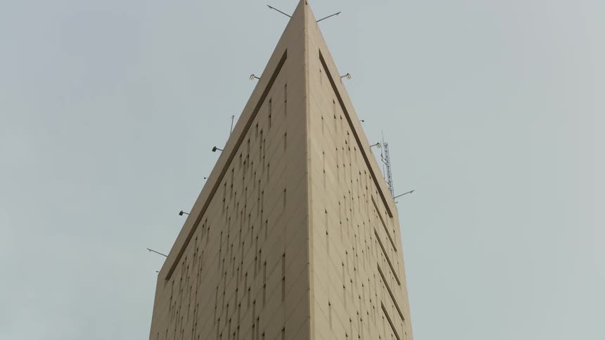 The top of a skyscraper has antennas and lights sticking out from it