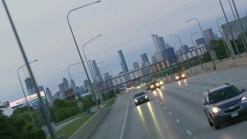 Twisting footage of vehicles driving down the highway near the city skyline