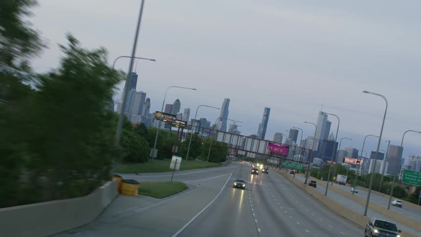 Tilting and rotating view of traffic leaving on a highway heading away from a large city