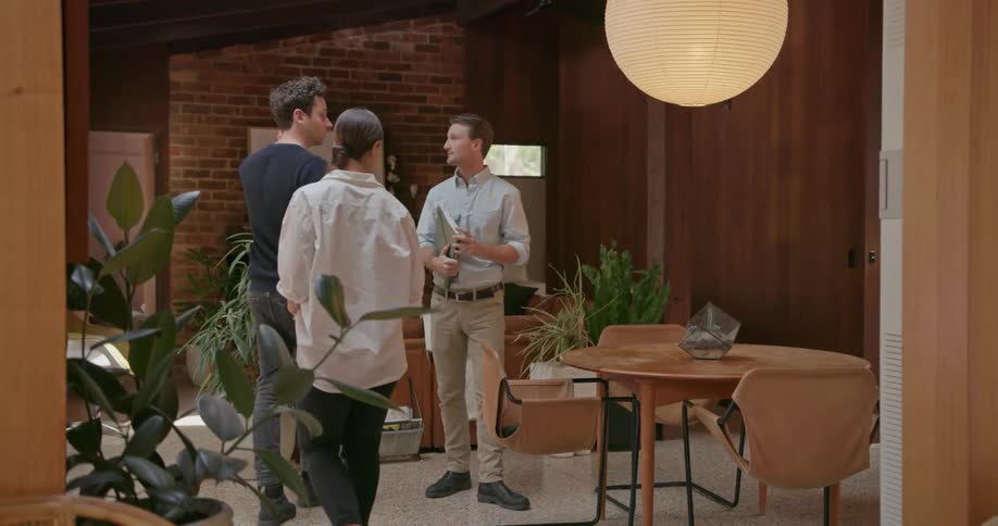 Two men and a woman look at the inside of a house