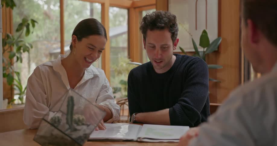 A man and woman are speaking to a man while looking over paperwork