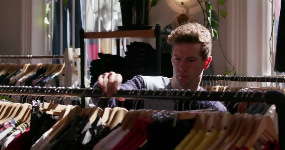 A man straightens the clothes hangers in a clothing store