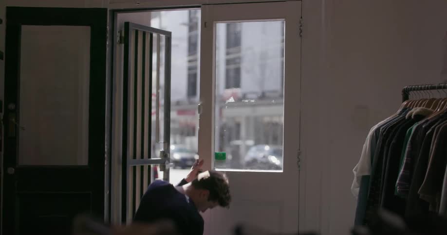 A man unlocks a store door and opens it