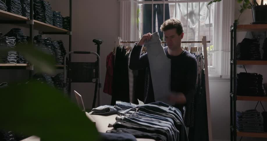 Man working in a clothing store folds pants