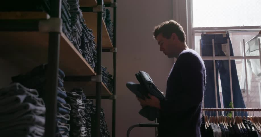 Man puts folded up pants on a store shelf