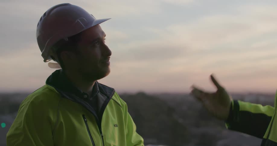 Construction workers talk outside at sunset
