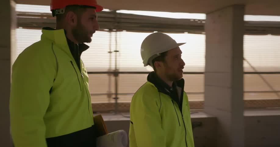 Two construction workers walk on a work site