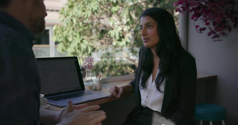 Woman and man sit by laptop talking