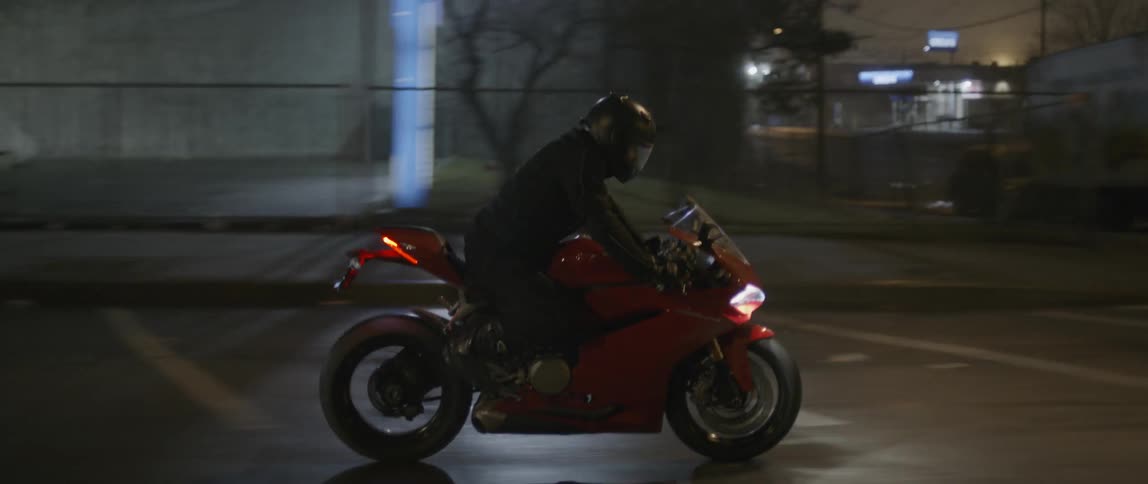 A person riding a red motorcycle down the road