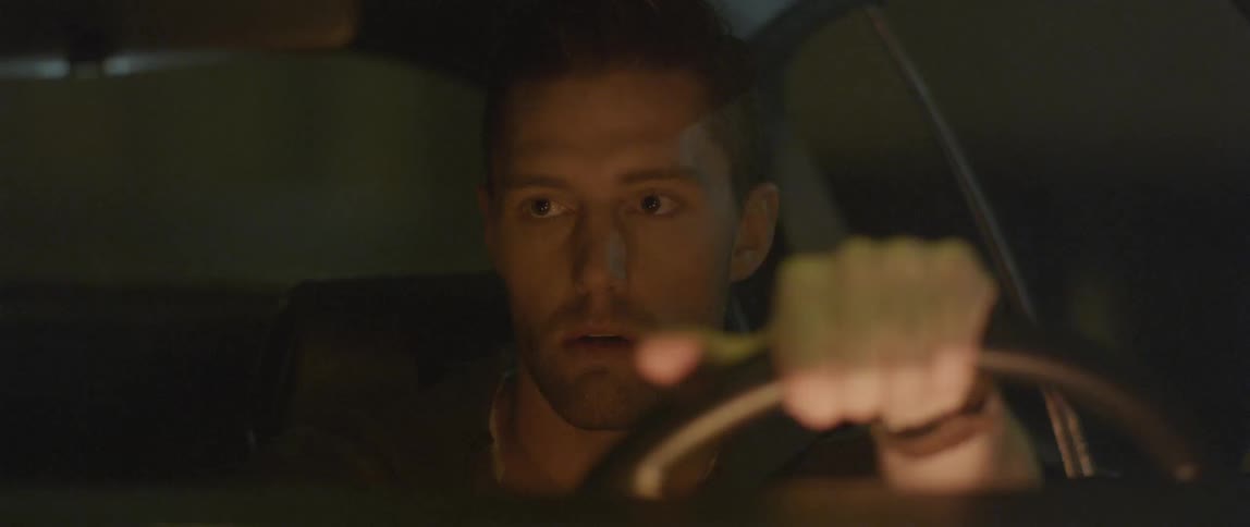A man drives while looking around