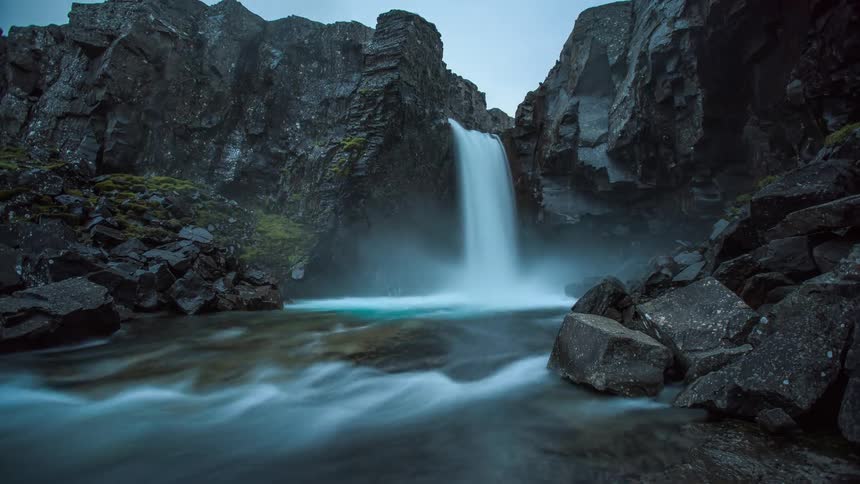 Waterfall cascades down the cliffside on a cloudy day