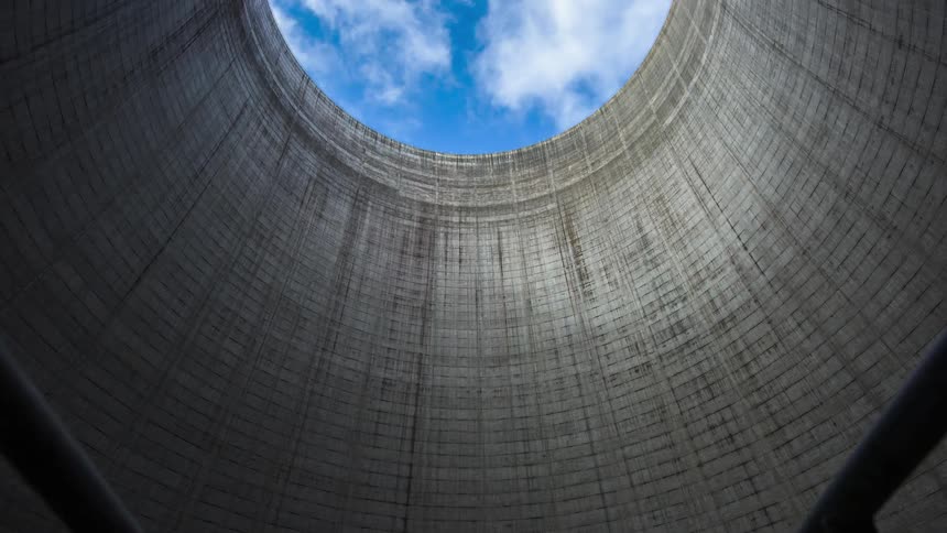 A timelapse shot creeping through the bottom of a nuclear power cooling tower as the camera pans up to the sky sky