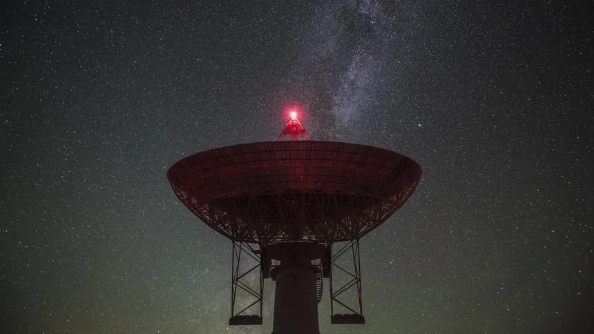 A timelapse shot of the radio telescope at the Owens Valley Radio Observatory with the stars and galaxy moving across the night sky