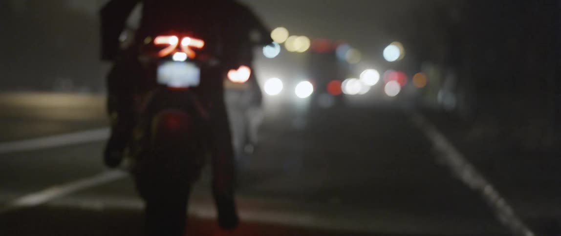 People ride motorcycles down a dark street