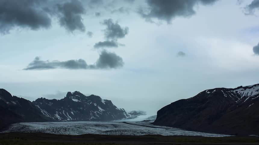 Clouds move over snow capped mountains