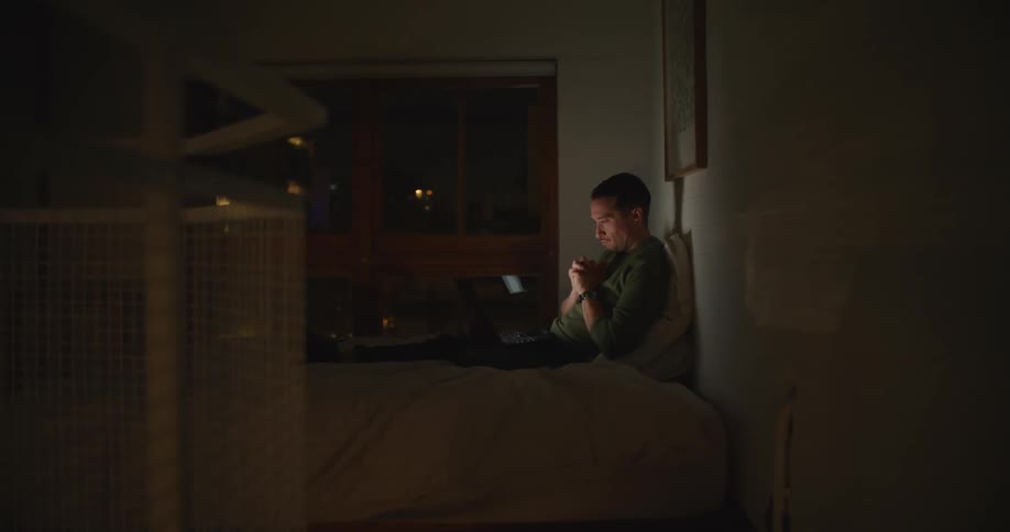 A man works on his laptop while sitting on a bean bag