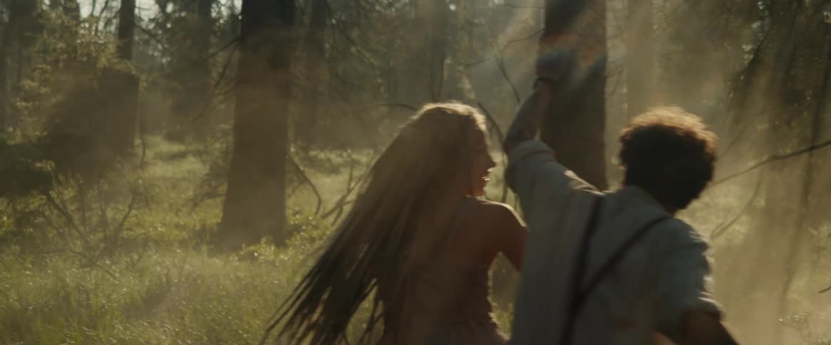 A man and woman dance around a tree in the woods