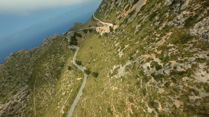 A winding curving road on the side of a mountain along the coast