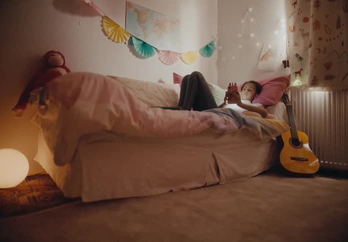 A young woman uses her smartphone while resting in on a sofa