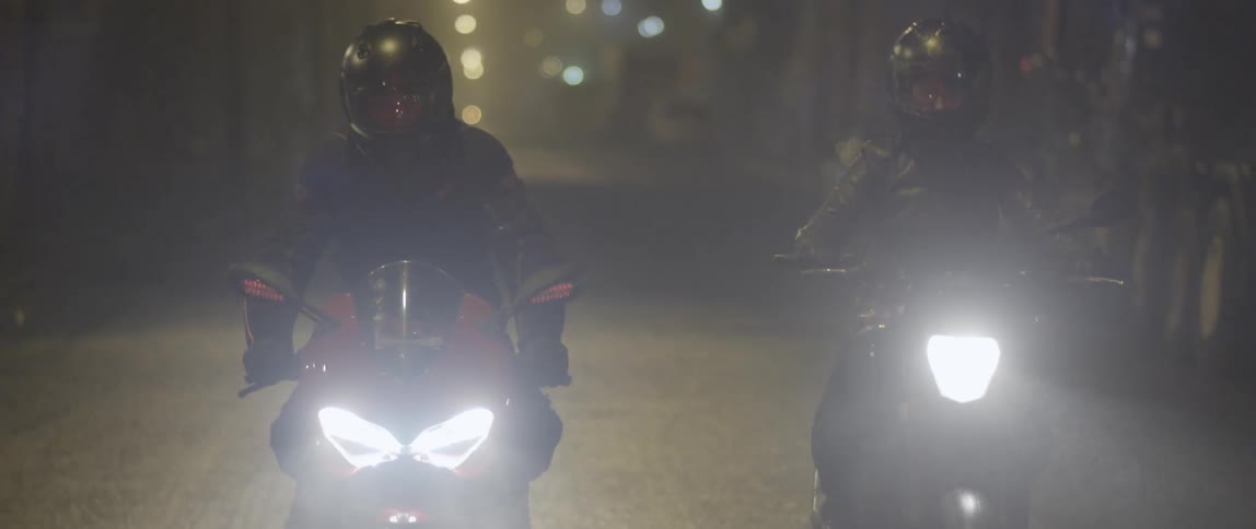 Two motorcycles driving down the road