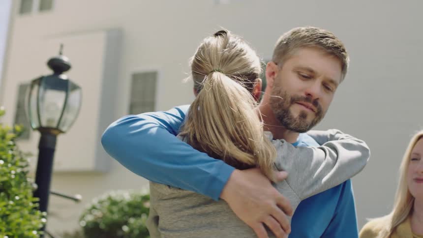 A daughter packs her stuff and hugs her parents