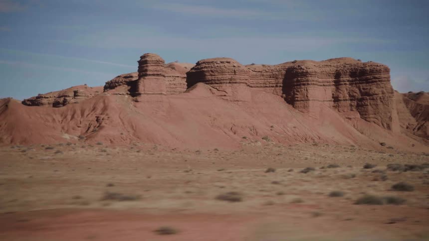 Red sand of badlands contrast with blue of sky near canyon
