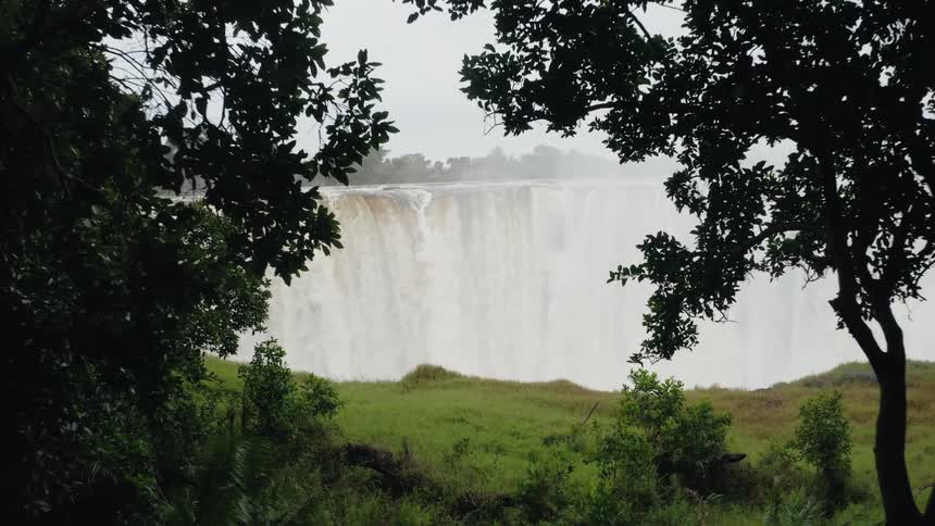 View through the trees of a powerful waterfall dropping into a canyon
