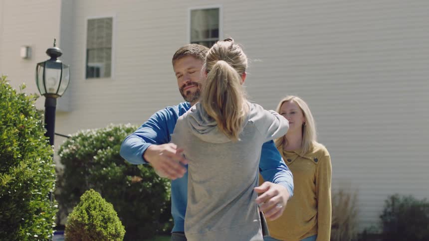 Parents hug college bound daughter after she finishes packing her car