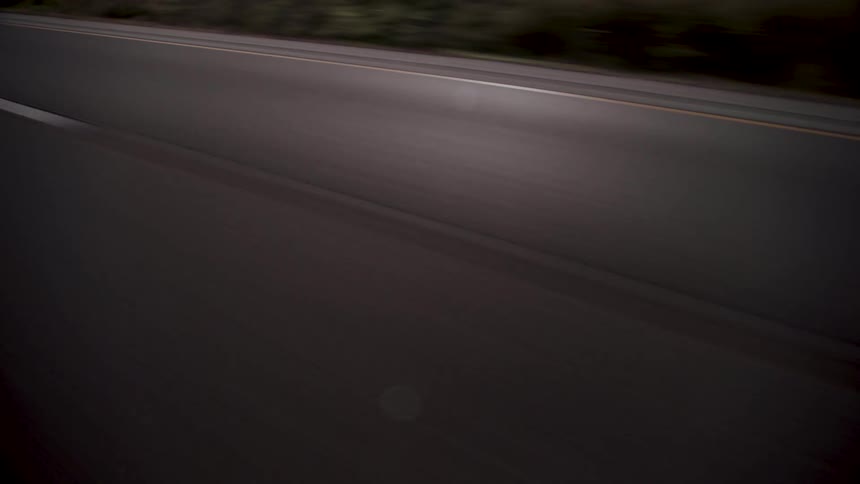 The painted lines of a highway go by quickly with movement