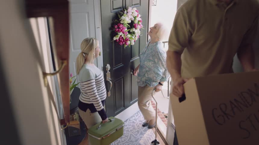 Young couple helps an elderly lady move into a new house